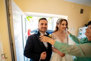Wedding party members interact in a warmly lit hallway with cream-colored walls.