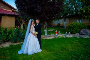 Newlyweds pose for romantic outdoor wedding photos on a manicured lawn at sunset.