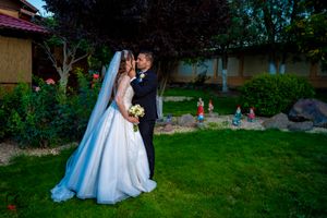 Wedding couple shares intimate moments while taking photos on landscaped grounds.