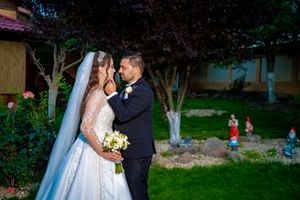 Bride and groom embrace during their outdoor wedding photoshoot in a garden setting.