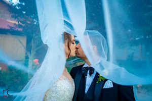 Artistic wedding photo with flowing veil and dreamy blue atmospheric lighting.