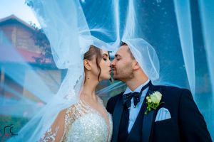 Intimate wedding portrait with dramatic veil and blue atmospheric lighting.