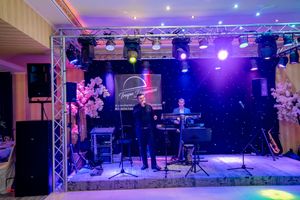 Wedding reception venue with purple stage lighting and professional audio equipment setup.