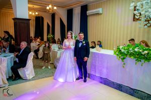 Elegant ballroom wedding reception with purple accent lighting and white table settings.