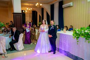 Wedding reception hall decorated with chandeliers and purple ambient lighting.