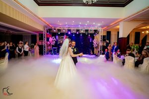 A magical wedding dance moment captured with atmospheric fog and dramatic purple stage lighting.