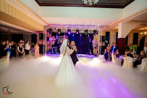 An elegant ballroom wedding reception with dramatic lighting and fog effects during the couple's dance.