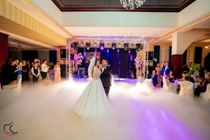 A romantic wedding dance scene with atmospheric fog effects and purple stage lighting in an elegant venue.