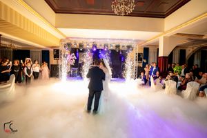 Wedding reception venue with fog-covered dance floor and purple-lit backdrop creating a dreamy atmosphere.