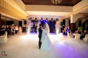 Elegant ballroom wedding dance with atmospheric lighting and fog creating a magical moment.