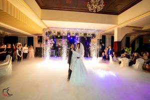 Wedding reception features a romantic dance under crystal chandeliers with purple lighting and fog effects.