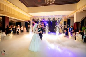 Wedding reception features dramatic lighting and fog effects as couple dances in an elegant ballroom.