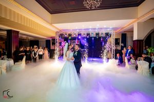Wedding reception in a luxurious venue with low-lying fog and dramatic purple stage lighting.