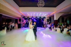 Elegant ballroom wedding reception with purple lighting and fog effects during the couple's dance.