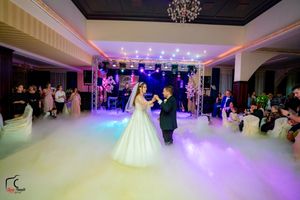 Wedding celebration in an elegant ballroom with dramatic lighting and atmospheric fog effects.