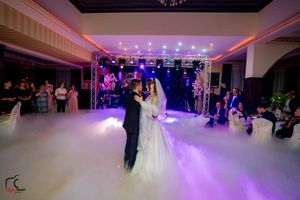 Couple's first dance in an elegant ballroom with atmospheric lighting and fog effects.