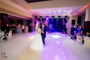 Wedding reception ballroom with purple lighting and fog effects on dance floor during first dance.