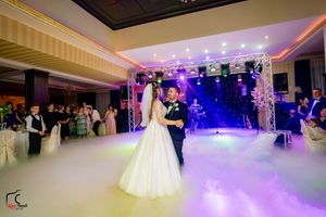 Elegant ballroom setup with dramatic purple lighting and low-lying fog for wedding celebration.