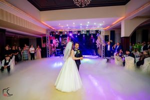 Wedding venue with chandelier and purple uplighting creating romantic atmosphere on dance floor.