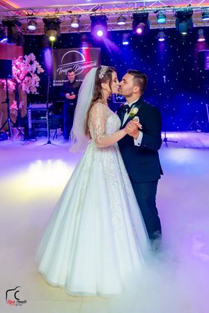 First dance at wedding reception with dramatic fog effect and purple lighting creating magical atmosphere.