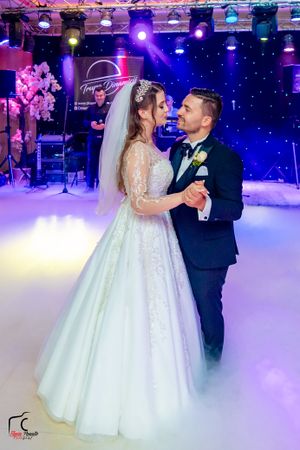 Couple sharing romantic dance moment on fog-covered dance floor with blue and purple lighting.