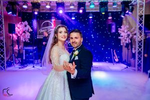 Ballroom wedding reception with professional lighting truss and atmospheric effects.