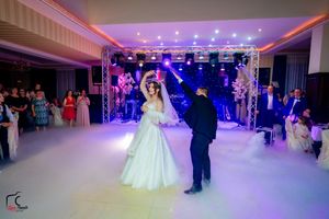 Wedding reception venue with elegant purple and blue lighting illuminating a spacious dance floor.