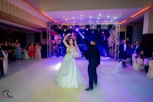 Large banquet hall with dramatic purple lighting and stage setup for a wedding reception.