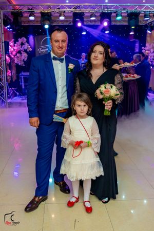 Wedding party members gathered on illuminated dance floor with formal attire and decorative lighting.