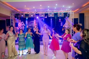 Wedding reception dance floor filled with guests dancing under vibrant purple and blue lights.