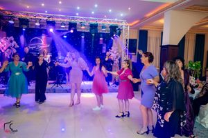 Panoramic view of wedding reception with guests dancing under colorful lighting effects.