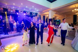 Wide view of wedding reception venue with guests dancing under purple ambient lighting.