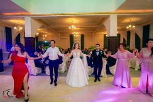 Wedding guests perform a synchronized dance routine on an illuminated dance floor during the reception celebration.