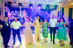 Guests dance in formation during a wedding reception with colorful stage lighting and truss system overhead.