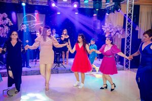 Group of dancers in colorful dresses perform synchronized moves on an illuminated dance floor.