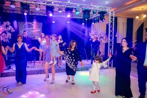 Guests enjoy dancing on an illuminated dance floor with professional lighting and sound equipment overhead.
