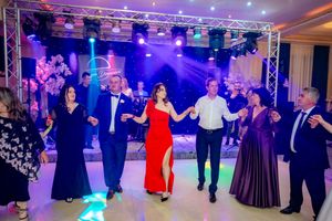 Wedding reception guests perform coordinated dance moves under theatrical lighting in an elegant ballroom.