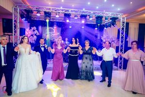 Wedding reception dance floor filled with guests dancing under purple and blue lighting and ceiling truss system.