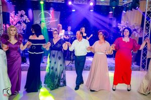 Formal event with dancers in evening wear moving across a ballroom under vibrant purple lighting.