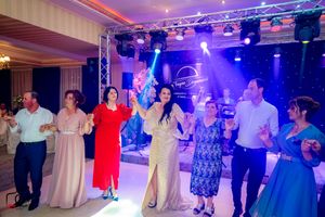 Formal dance party with guests in elegant attire moving across a purple-lit ballroom floor.