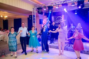 Couples dancing at an elegant ballroom event with dramatic purple stage lighting and truss rigging overhead.