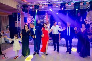 Wedding guests dancing in formal attire under dramatic purple stage lighting and truss system.