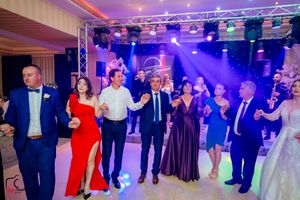Formal event dancers spread across ballroom floor illuminated by purple theatrical lighting.