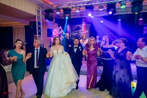 Wedding party dancing together under purple stage lighting at an elegant reception venue.