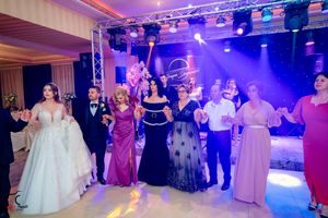 Wedding party dancing in a line formation under dramatic purple and pink lighting effects.