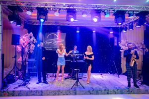 Live band performing on stage with professional lighting and sound equipment at wedding reception.