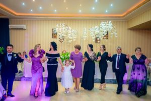Wedding party dancing in formation under elegant chandeliers in a beautifully lit ballroom.