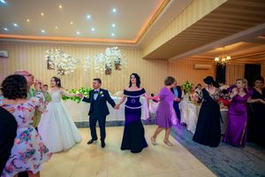 Wedding reception dance with guests in purple and formal attire on a wooden dance floor.