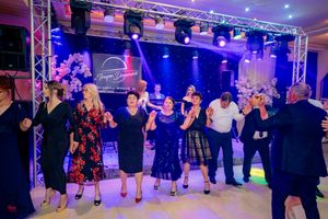 Reception guests performing a coordinated line dance under dramatic blue stage lighting.