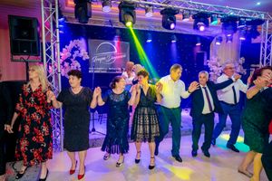 Party guests dance in a line formation under colorful stage lighting and professional event rigging.